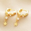 Pearl and Crystal Star Charm Huggie Hoop Earrings in Gold on Beige Fabric