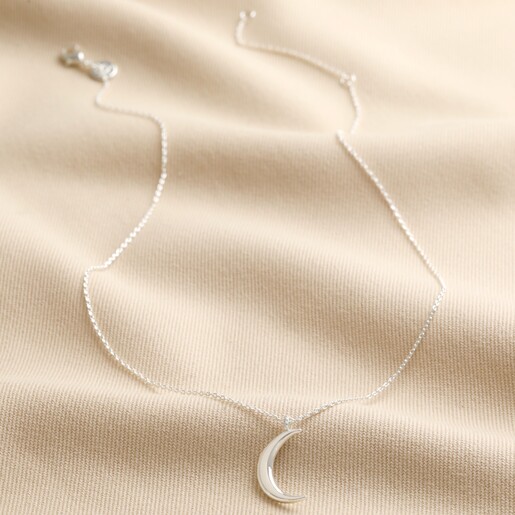 Crescent Moon Pendant Necklace in Silver on top of beige coloured fabric