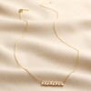 Full Chain of Crystal Baguette Bar Necklace in Gold on Beige Fabric
