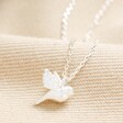 Delicate Bird Pendant Necklace in Silver on top of beige coloured material