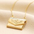Envelope Locket Necklace in Gold on top of beige coloured fabric