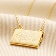 Back of Envelope Locket Necklace in Gold on top of beige coloured fabric