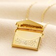 Envelope Locket Necklace in Gold open on top of beige coloured fabric
