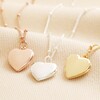 Heart Locket Necklace in Gold with rose gold and silver necklaces against beige backdrop