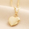 Heart Locket Necklace in Gold against beige coloured fabric