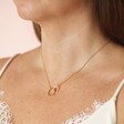 Close up of Organic Interlocking Hoops Necklace in Gold on model with brown hair against neutral backdrop