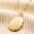 Oval Locket Necklace in Gold on top of beige coloured fabric