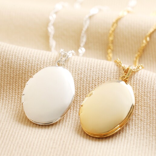 Oval Locket Necklace in Gold with silver version on neutral coloured fabric