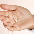 Model holding Pearl and Crystal Moon and Stars Necklace in Gold in palm of hand