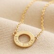 Close up of Personalised Eternity Ring Pendant Necklace in gold against beige coloured material