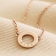 Close up of Personalised Eternity Ring Pendant Necklace in rose gold against beige 