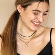Model smiling looking down wearing Personalised Talisman Satellite Chain Pendant Necklace in Gold in curated look