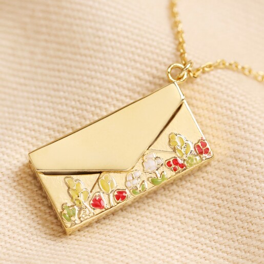 Close up of Personalised Wildflower Envelope Locket Pendant Necklace in Gold closed on top of beige coloured fabric