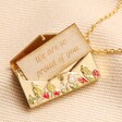 Personalised Wildflower Envelope Locket Pendant Necklace in Gold open with token coming out on top of beige coloured fabric