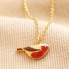 Enamel Robin Pendant Necklace in Gold on top of beige fabric