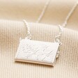 Back of Envelope Locket Necklace in Silver on top of beige coloured material
