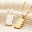 Close up of Tiny Hammered Tag Pendant Necklace in Silver with gold version on top of beige coloured material