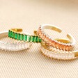 Adjustable Green Baguette Crystal Band Ring in Gold with other colours stacked on top of neutral coloured backdrop