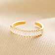 Adjustable Clear Baguette Crystal Band Ring in Gold on top of beige coloured fabric