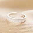 Adjustable Clear Baguette Crystal Band Ring in Silver laid on top of beige coloured fabric