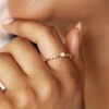 Close Up of Model Wearing Dainty Pearl and Crystal Stacking Ring in Gold With Hand Under Chin