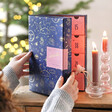 Model reaching out to Personalised Fill Your Own Celestial Advent Calendar on top of table top with lit candles
