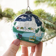 Model Holding Hand-Painted Norfolk Bauble While It's Hanging in Christmas Tree
