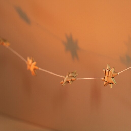 Afroart Natural Stars on a String Garland in warm lighting in front of neutral backdrop