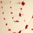 Afroart Red Stars on a String Garland hanging in front of neutral background