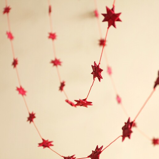 Afroart Red Stars on a String Garland hanging in front of neutral background