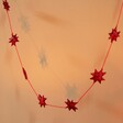 Afroart Red Stars on a String Garland hanging in front of neutral background in warm lighting