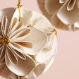 Close up of Afroart Set of 2 White and Gold Flower Ball Hanging Decorations with other decoration behind