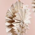 Close up of Afroart Set of 2 White and Gold Layered Pinwheel Hanging Decorations against neutral background