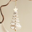 Afroart White and Gold Christmas Tree Hanging Decoration hanging from tree branch against neutral background