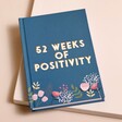 Teal Floral 52 Weeks of Positivity Diary on top of raised surface with beige backdrop
