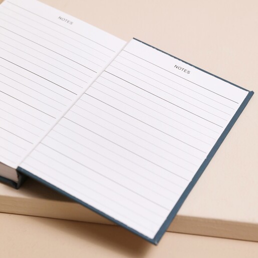 Teal Floral 52 Weeks of Positivity Diary open on inside page on top of beige coloured surface