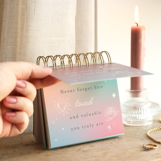 Model flipping through Celestial Positivity Flip Chart on top of wooden surface