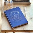 Closed Blue Celestial Positivity Planner in Lifestyle Shot on wooden surface