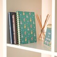 Teal Dog Lined Notebook in lifestyle shot on shelf with reed diffuser