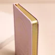 Close up of page edges on Pink Sun and Moon Fabric Notebook with beige background