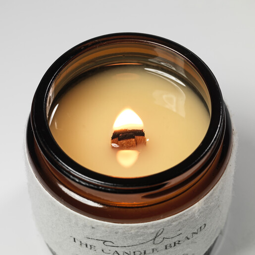 The Candle Brand Lemongrass and Geranium Scented Candle lit against white background