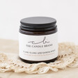 The Candle Brand Ylang Ylang and Sandalwood Scented Candle on top of natural coloured cloth with white background