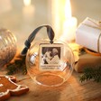 Personalised Photo Glass Dome Bauble on wooden surface surrounded by Christmas decorations