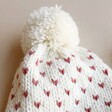 Close Up of Bobble on White and Pink Knitted Bobble Hat and Mittens Set
