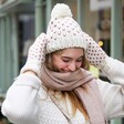 Model Wearing White and Pink Knitted Bobble Hat and Mittens Set and Adjusting Hat