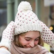 White and Pink Knitted Bobble Hat and Mittens Set on Model Pulling Hat Down