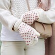 Model Putting on Mittens from White and Pink Knitted Bobble Hat and Mittens Set