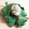 House of Disaster Secret Garden Hedgehog Hot Water Bottle with hedgehog coming out of leaf on top of neutral coloured backdrop