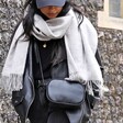 Model wearing Rectangular Crossbody Bag in Black with grey scarf in front of wall