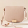 Vegan Leather Crossbody Bag in Pink on top of raised surface against neutral backdrop